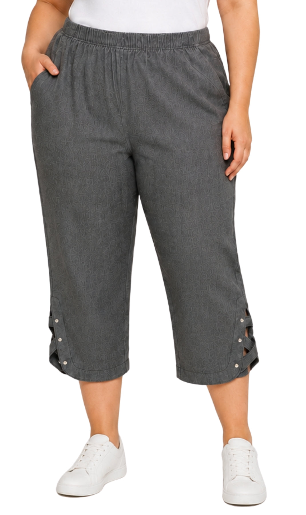 A person wearing dark gray cropped pants with side lace-up details and white sneakers, shown from the waist down on a plain white background.