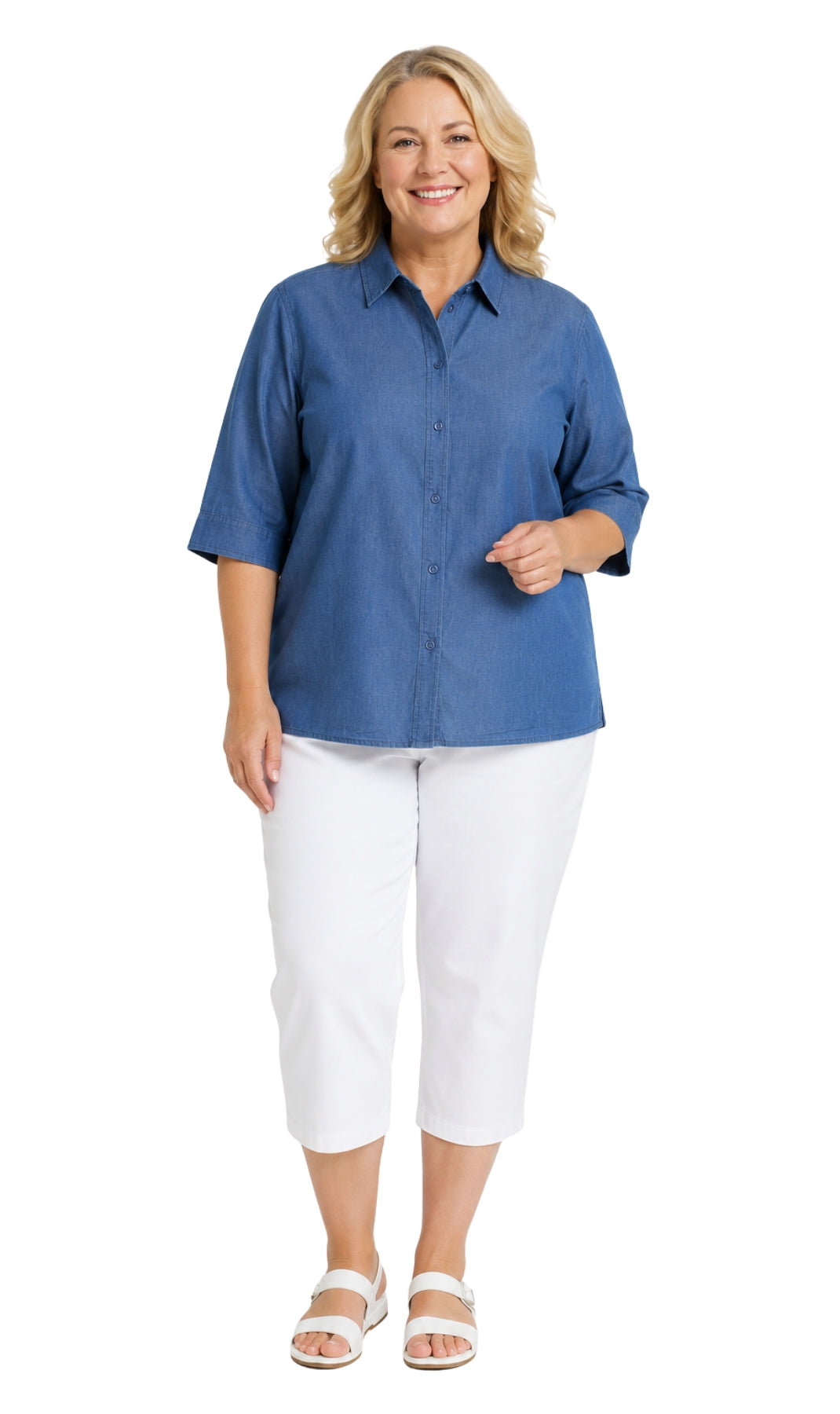 A woman modeling a blue short-sleeve button-up shirt with white cropped pants and white sandals, standing against a plain white background.